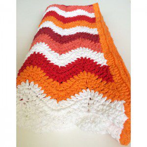 Orange crochet blanket on the floor